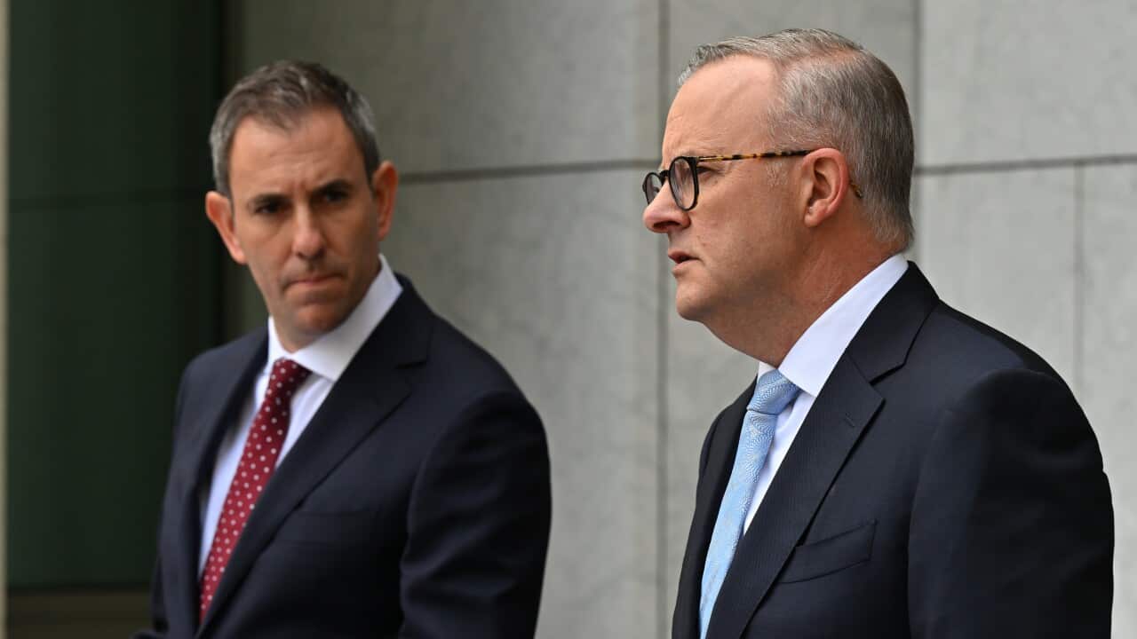 Two men wearing suits and ties standing at lecterns.