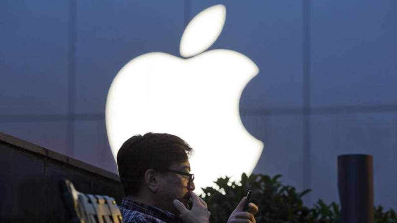 In this Friday, May 13, 2016, file photo, a man uses his mobile phone near an Apple store in Beijing, China. Apple Inc. reports financial results Tuesday, January 31, 2017.