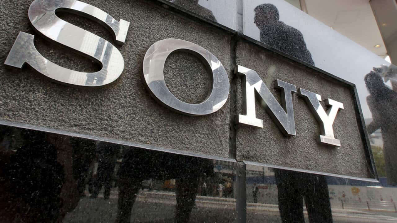 People are reflected on a wall of the Sony building in Tokyo