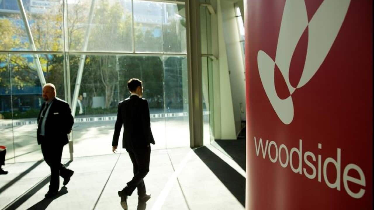 Shareholders walk past Woodside Petroleum signage in Perth.