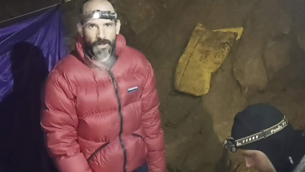 Mark Dickey is wearing a headlight in a cave.