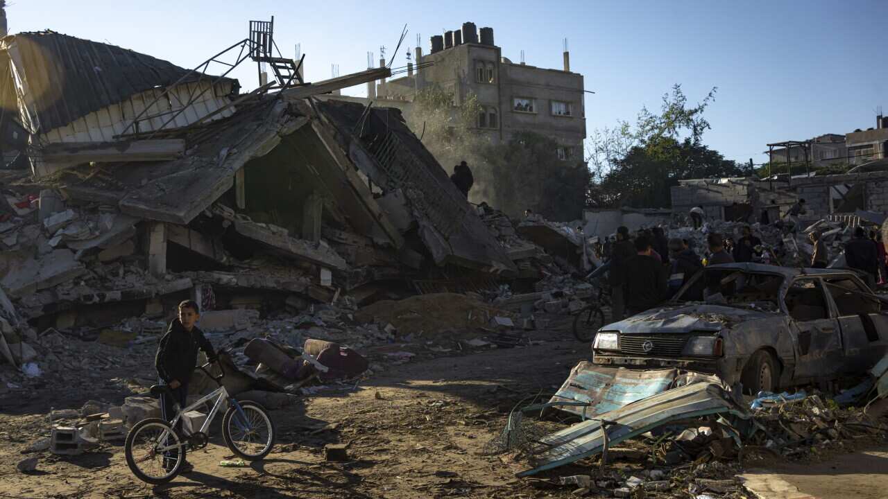A child with a bicycle stands in front of a destroyed building in Gaza