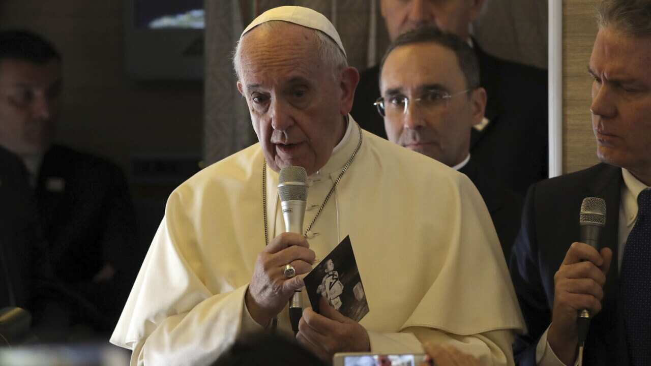 Pope Francis holds a photo of U.S. photographer Joseph Roger O'Donnell of child victims of Nagasaki bombing, aboard his flight to Santiago, Chile, Monday, Jan. 15, 2018.