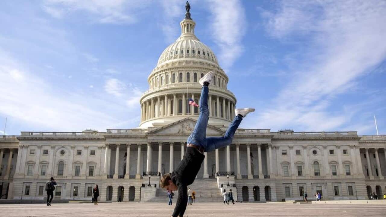 A visitor does a handstand in front of the shuttered US Capitol
