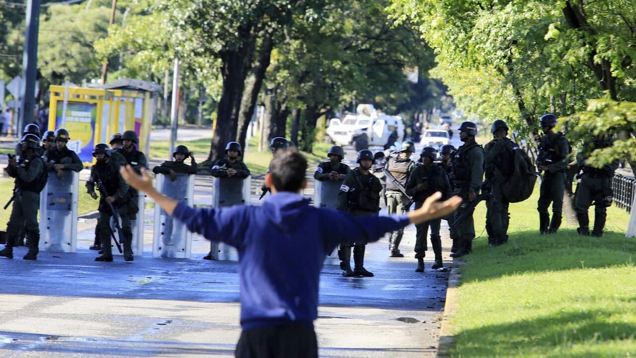 A man argues with a lineup of Venezuelan Bolivarian National Guards officersoutside of Military base Paramacay in Valencia, Venezuela.