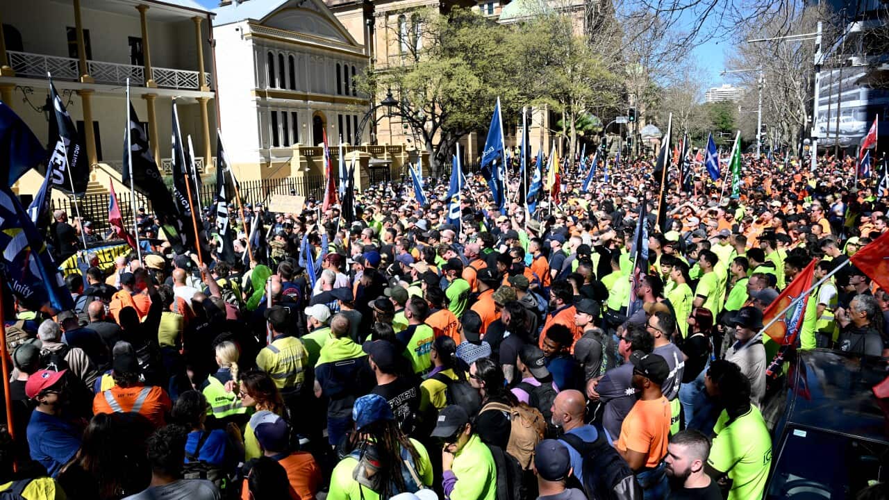A large group of protesters, many in hi-vis, standing out the front of a building.