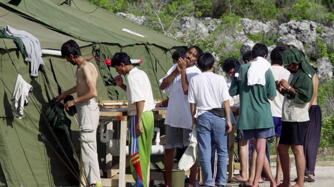 In this Sept. 21, 2001, file photo, men shave, brush their teeth and prepare for the day at a refugee camp on the Island of Nauru.