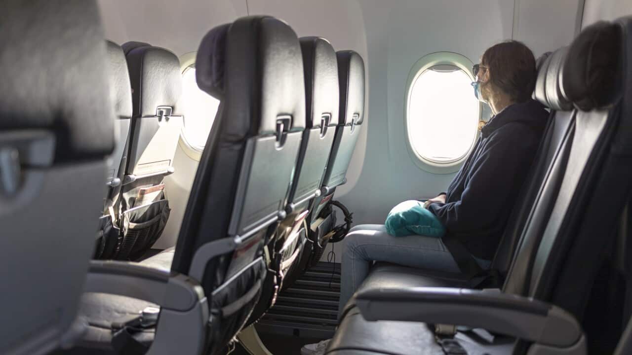 Air travel, passenger looking out airplane window, empty seats, COVID-19