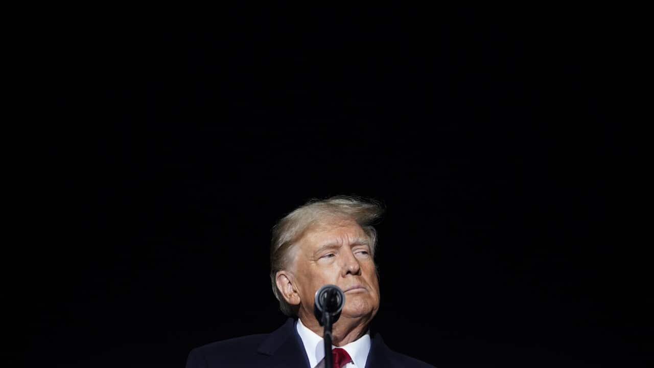 A man stands in front of a microphone