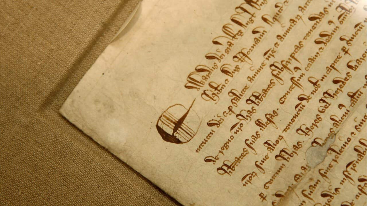 An ancient document with calligraphic writing, turned pale with age, lies on a surface.