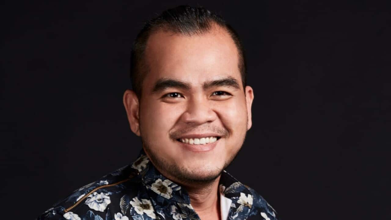 A man looks forward in a floral shirt, smiling