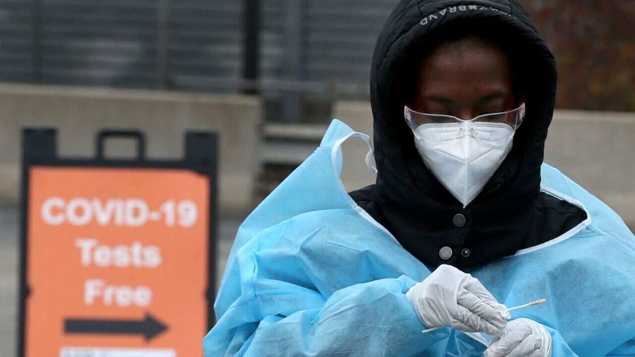 A health worker places a cotton swab into a tube after administering a COVID-19 test at the Foreman Mills Shopping Center in Chicago on Oct. 19, 2020