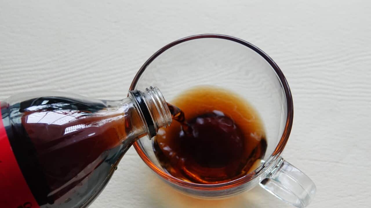Sugar-free Coca-Cola is poured from a plastic bottle into a glass cup.