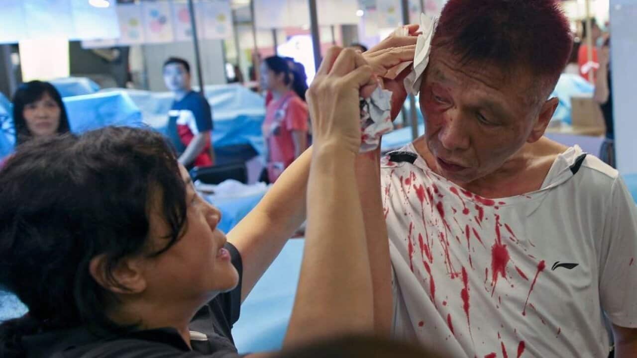 A man bleeding from a head injury is assisted by a woman after anti-government protesters and pro-China supporters clashed at a shopping mall in Hong Kong.