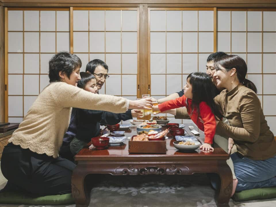 Japanese mulit generation family drinking a toast before eating Osechi Ryori, Japanese New Year dishes, on the dining table in Japanese room