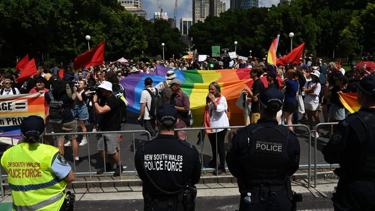 Police standing behind a barrier watching protesters.