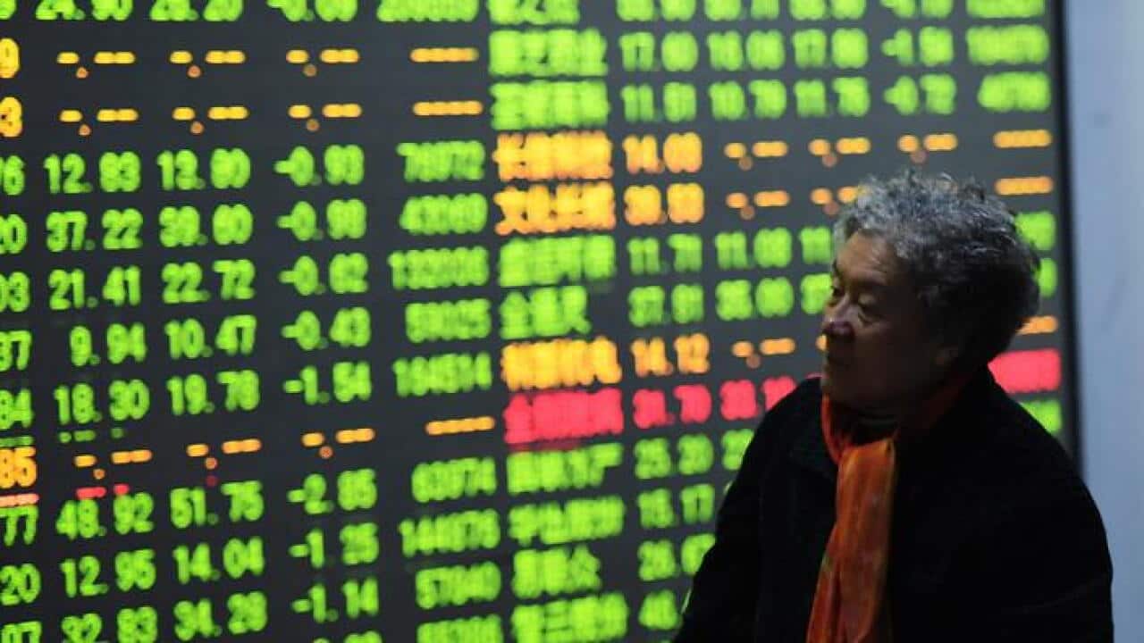 A woman walks past a screen in the brokerage house in Hangzhou, Zhejiang province, China. (AAP)