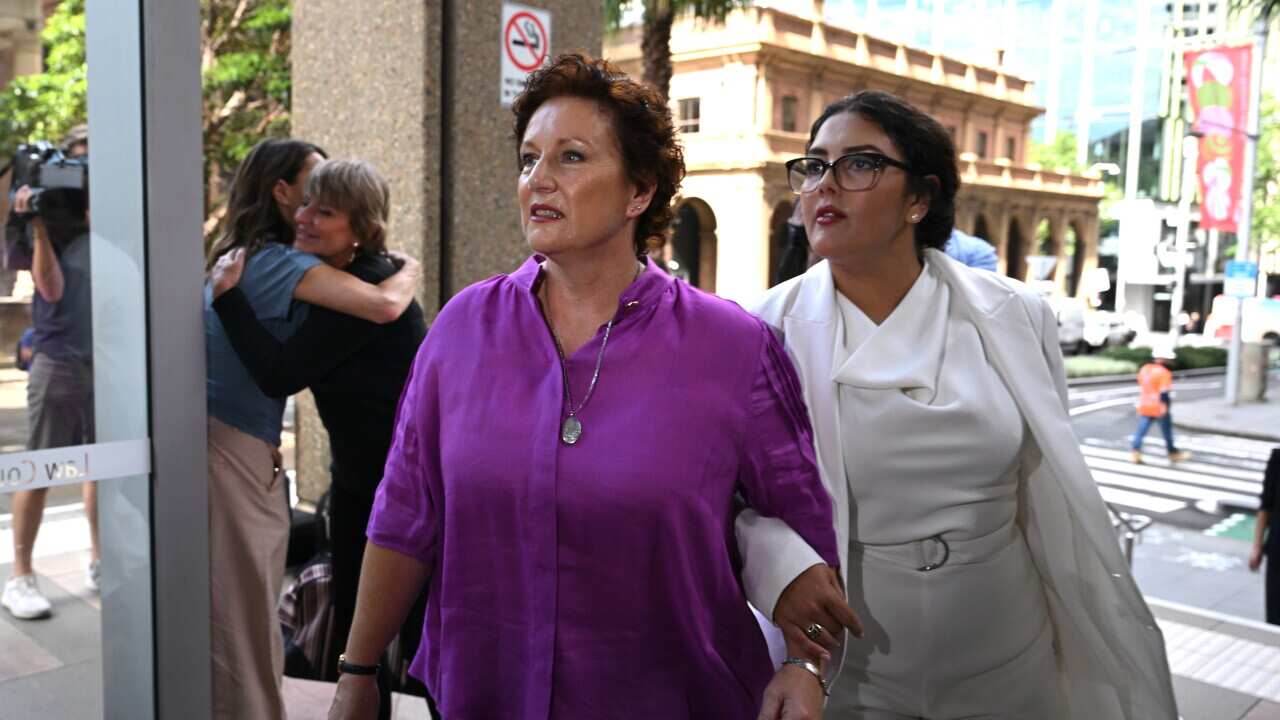A woman linked in arms as they enter a building.