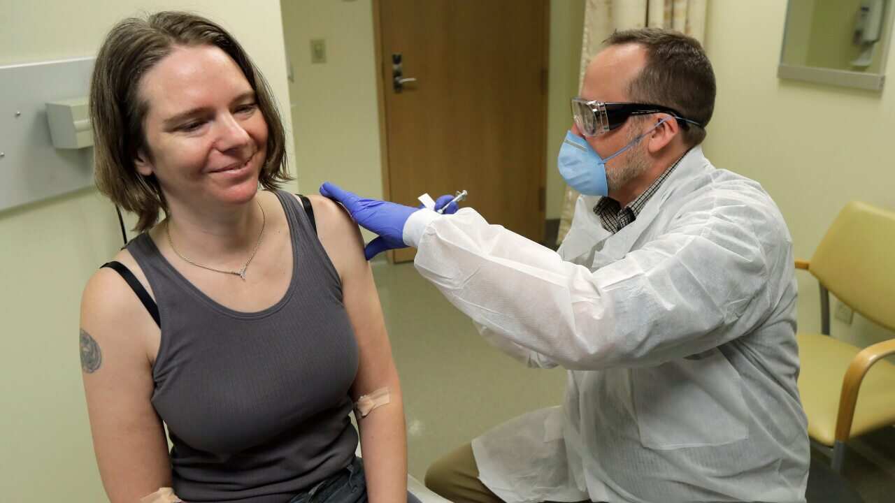 Jennifer Haller, left, smiles as she s given the first shot in the safety study clinical trial of a potential vaccine for the coronavirus in Washington.