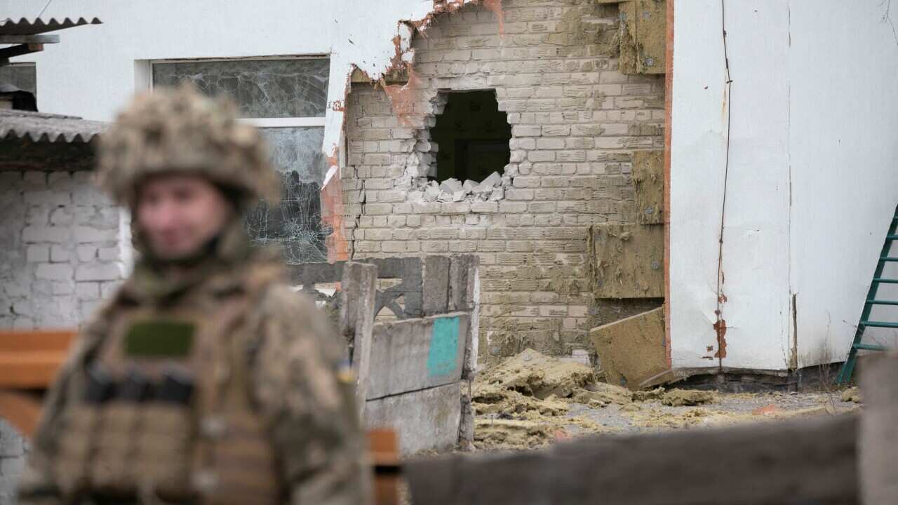 A Ukrainian soldier stands next to a damaged wall after the reported shelling of a kindergarten in the settlement of Stanytsia Luhanska, Ukraine,