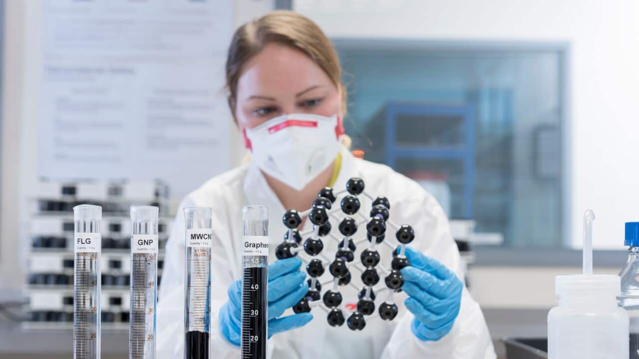 Female scientist with graphene nano material molecular model in graphene processing factory