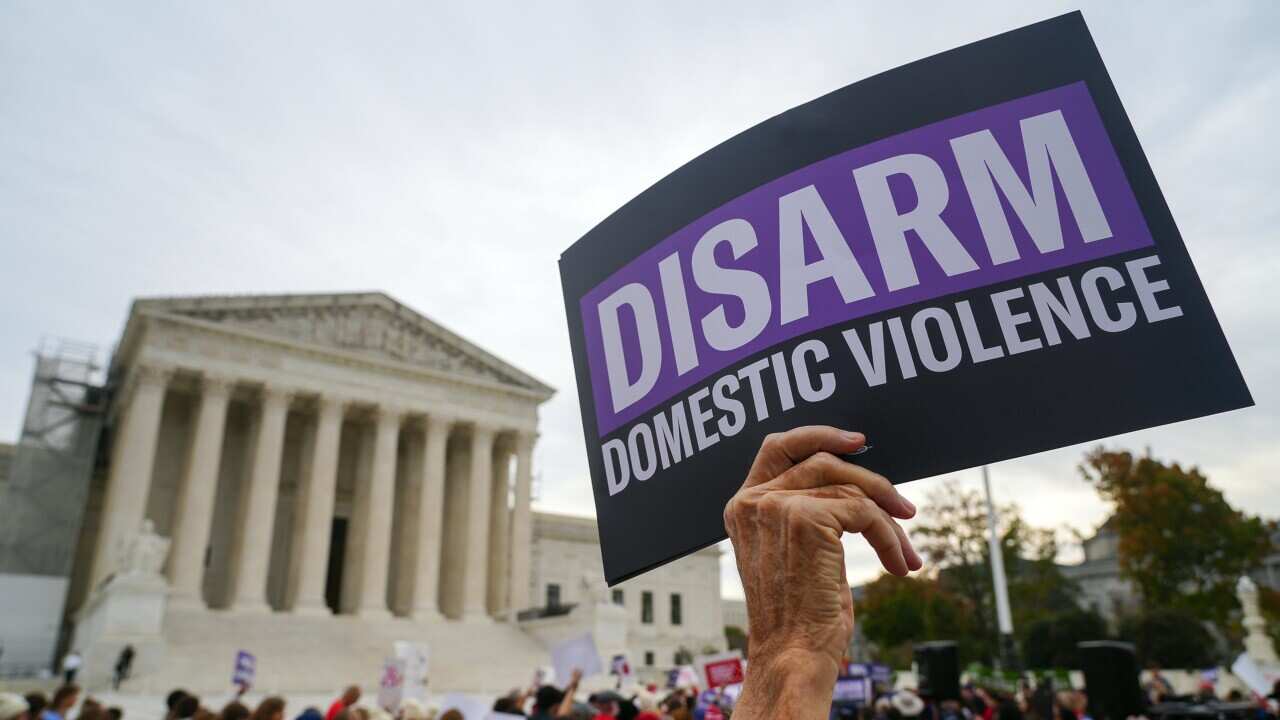 A protestor holds a sign saying 'Disarm domestic violence' outside the Supreme Court.