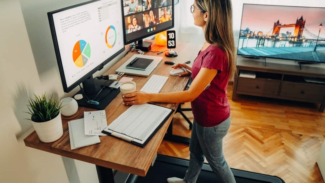 Woman at standing desk home office talking on business video call