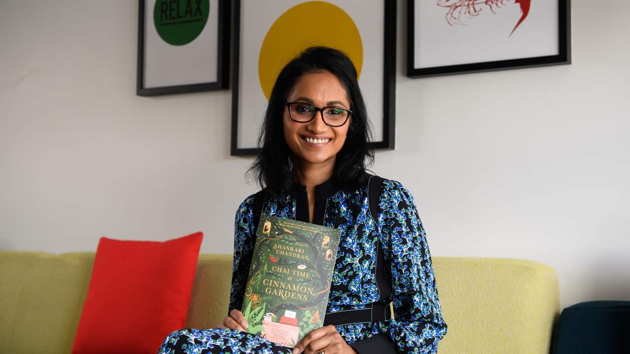 Shankari Chandran, sitting on a couch, poses for a portrait with her novel Chai Time at Cinnamon Gardens.