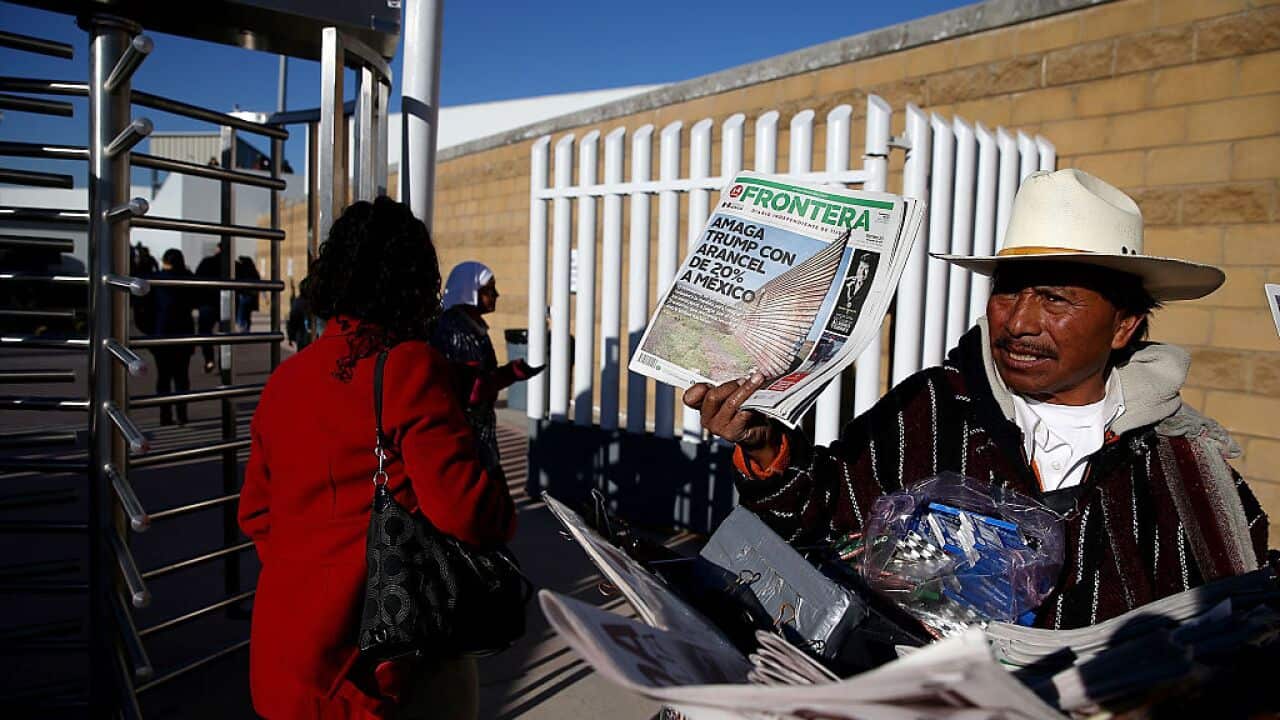 A newspaper vendor in Tijuana, Mexico, holds a newspaper with a front page story about Trump's proposed tax on Mexico to pay for a border wall.