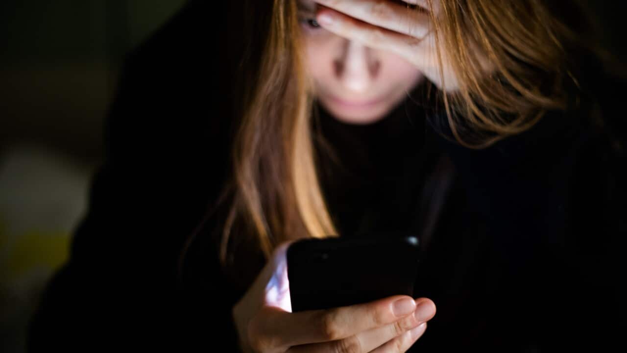 A distressed woman looks at her phone
