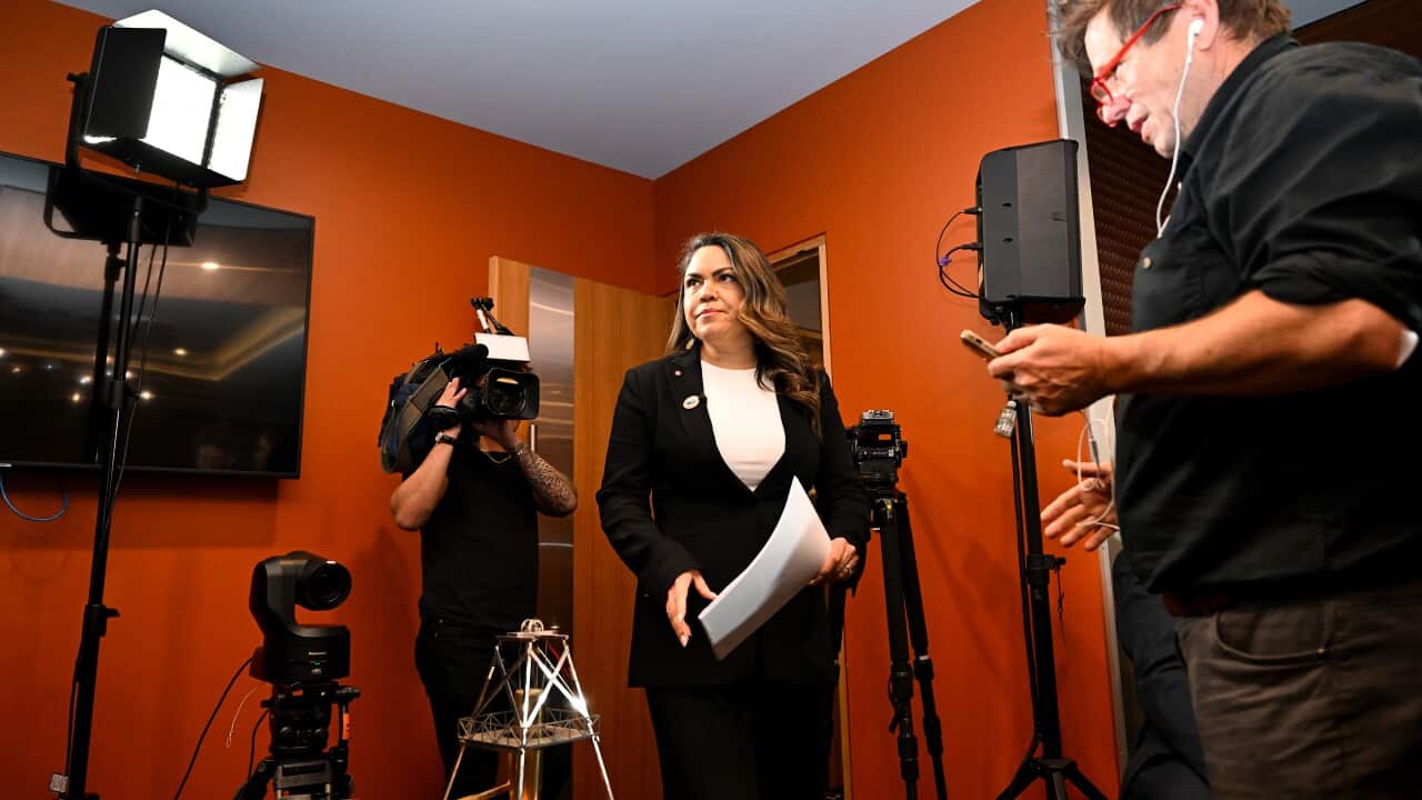 Jacinta Price stands in front of a camera operator with sheets of paper in hand.