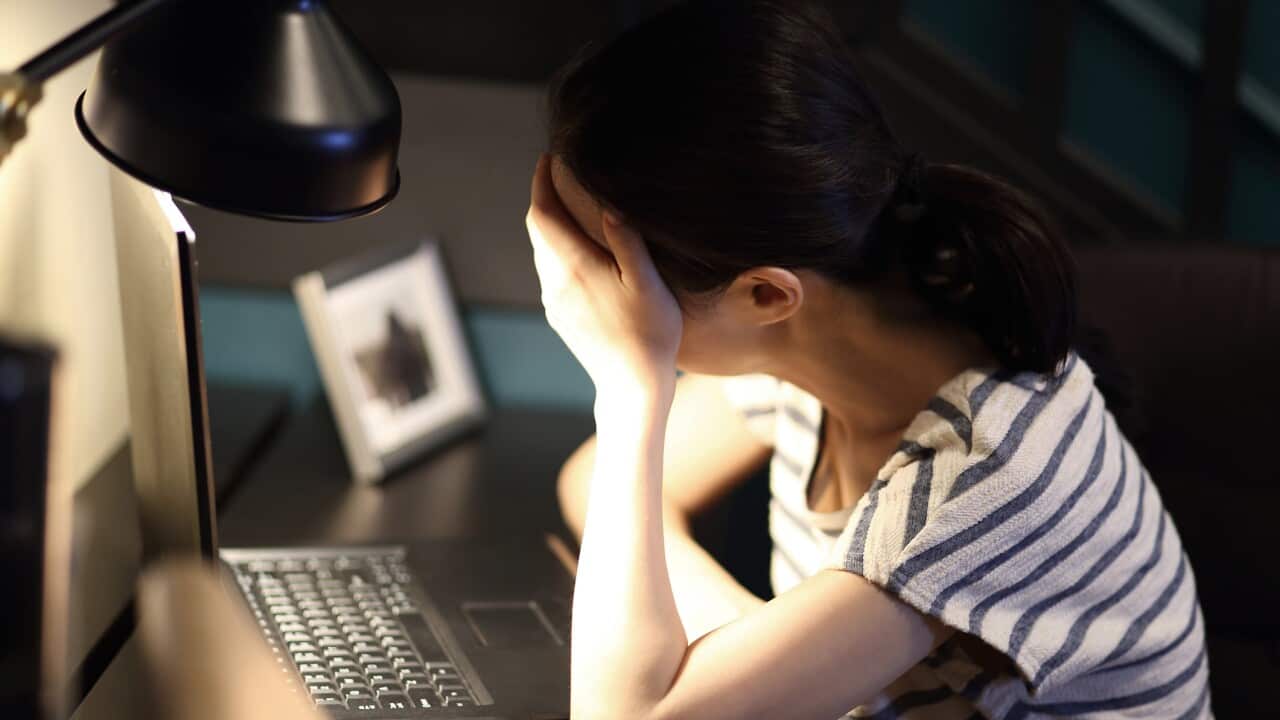 Tired woman with head in hand on desk at home