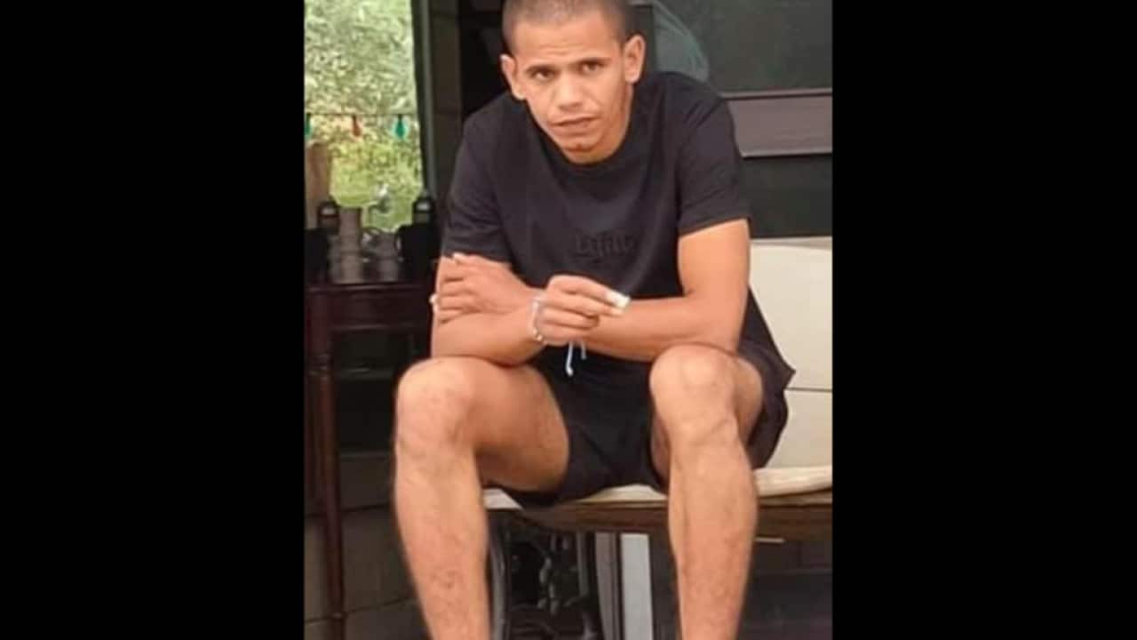 a thin indigenous man in trainers, shorts and a tshirt.