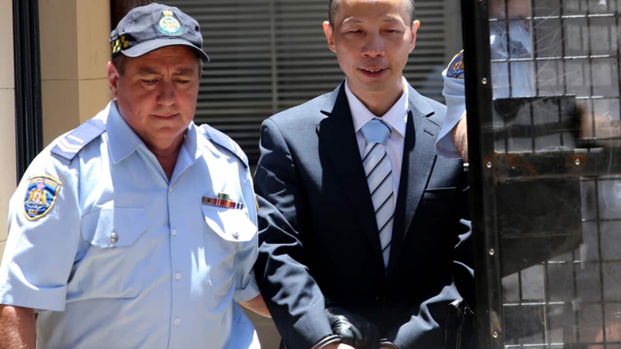 Lian Bin "Robert" Xie smiles as he is taken to a prison van
