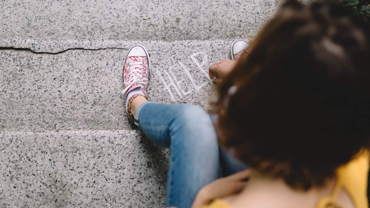 Teenage grl sitting on a staircase writing help wanted sign with chalk.