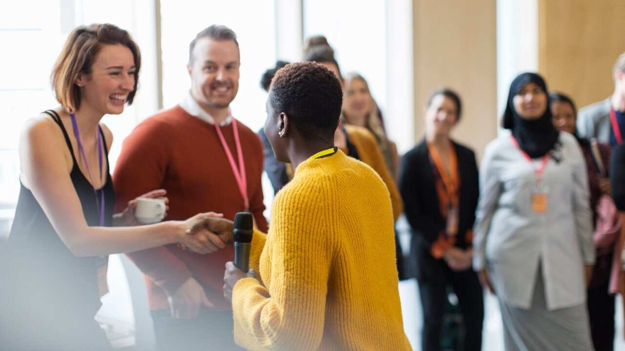 Businesswoman shaking hands with speaker at conference