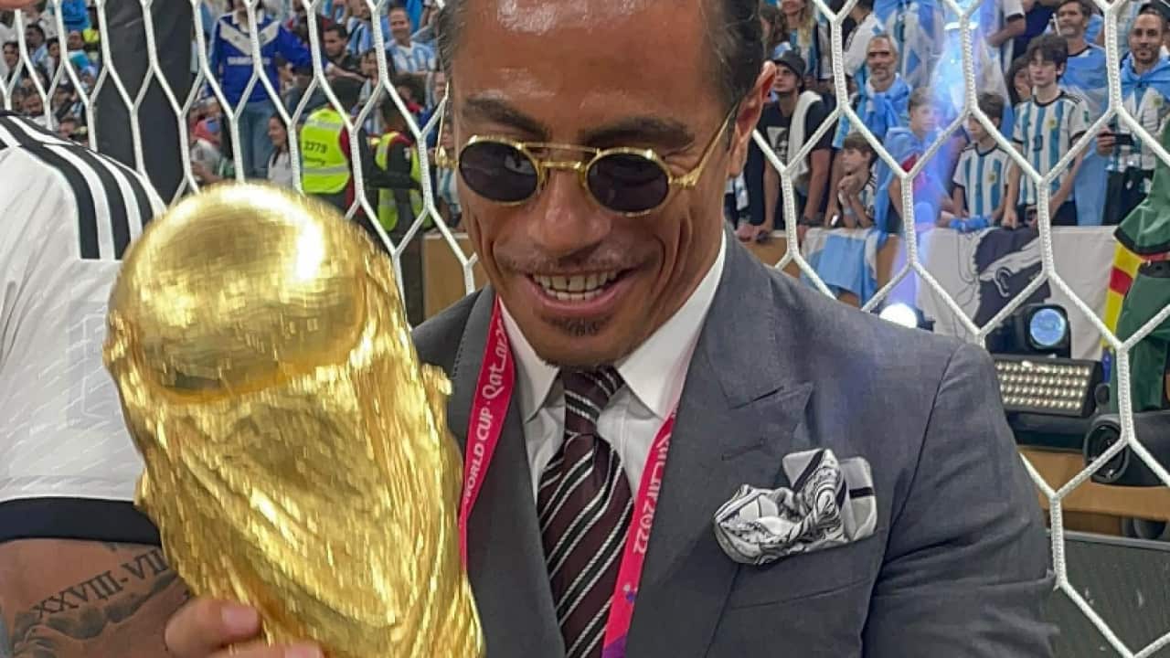 Man in a suit carries trophy.