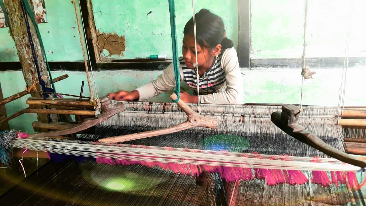 A young girl working a loom in an Indian workshop