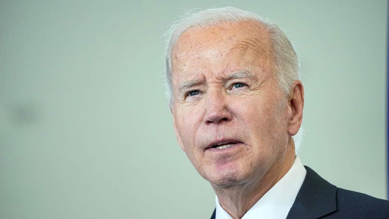 An old man with white hair dressed in a dark suit.