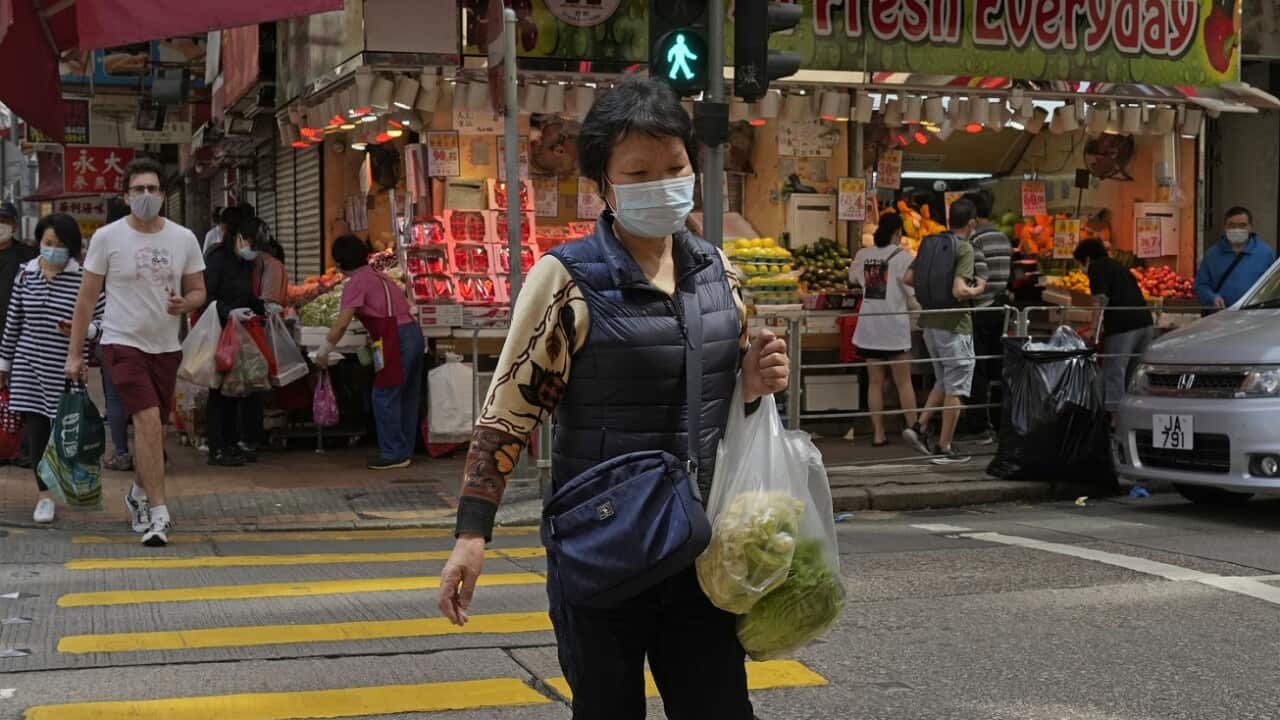 A woman wearing a face mask carries produce across a street in Hong Kong, March 13, 2022.