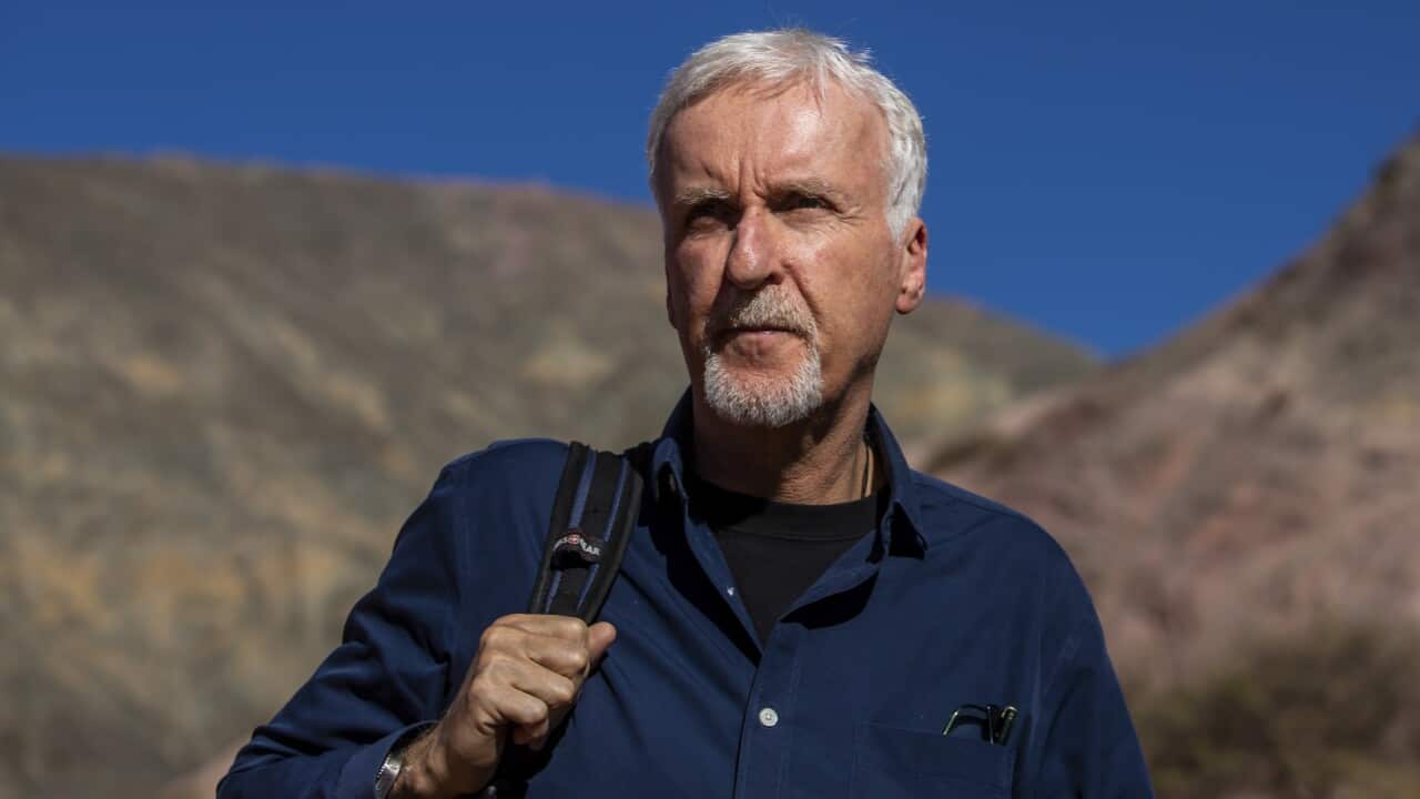 James Cameron standing outside with a bag on his back.