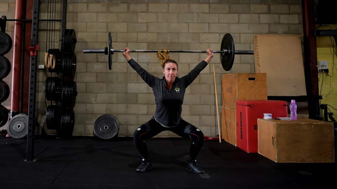 A woman lifts weights at a gym