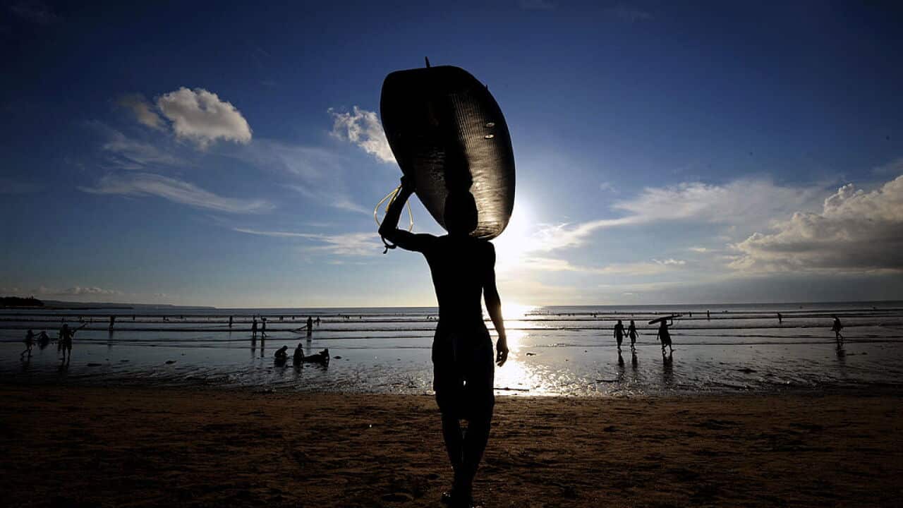 A surfer carries a surf board at Kuta be