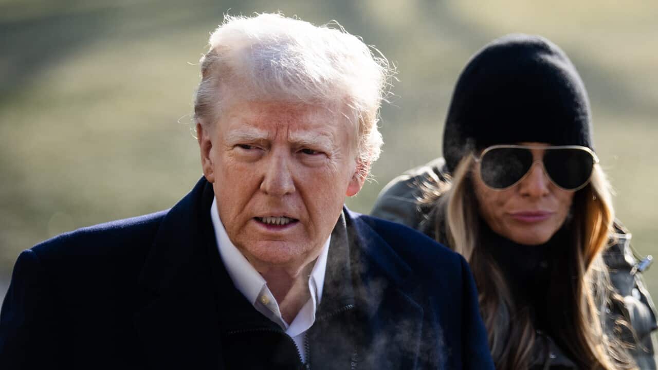 A man in a navy coat and a woman wearing sunglasses and a puffer jacket