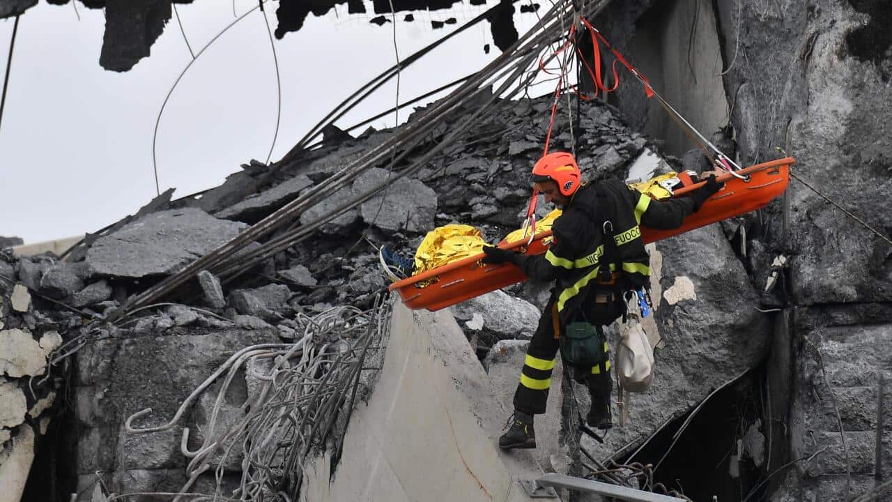 Firefighters rescue a person from the rubble of the collapsed Morandi highway bridge in Genoa, northern Italy, Tuesday, Aug. 14, 2018.