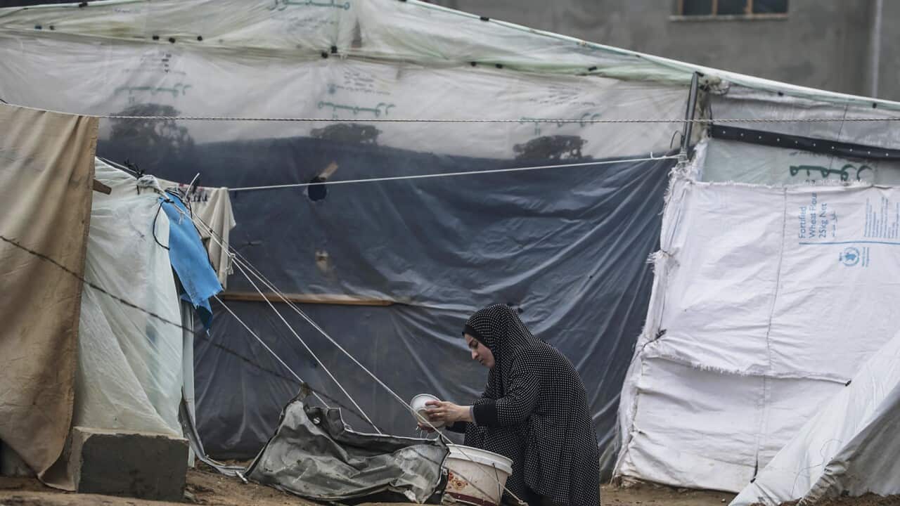 A Palestinian woman who fled from Rafah town, cleans dishes outside her shelter in Deir Al Balah, southern Gaza Strip (AAP).