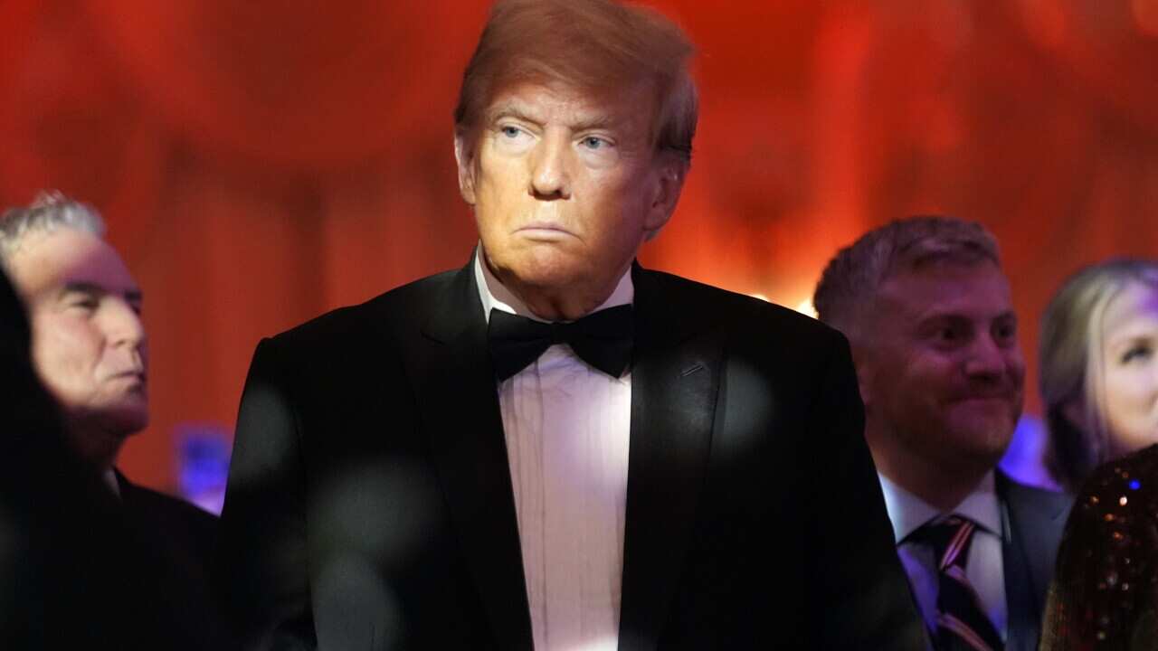 Donald Trump in a tuxedo in front of a red background.