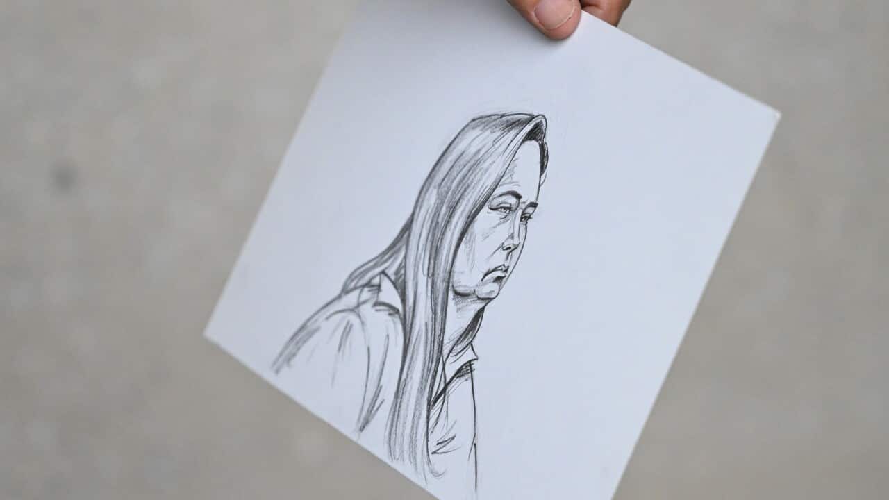 A hand holds a sketch of a woman with long hair and a serious expression.