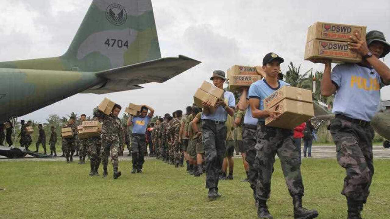 Filipino troopers carry relief goods out of a military plane as it lands at the airport in Baler province, northern Philippines