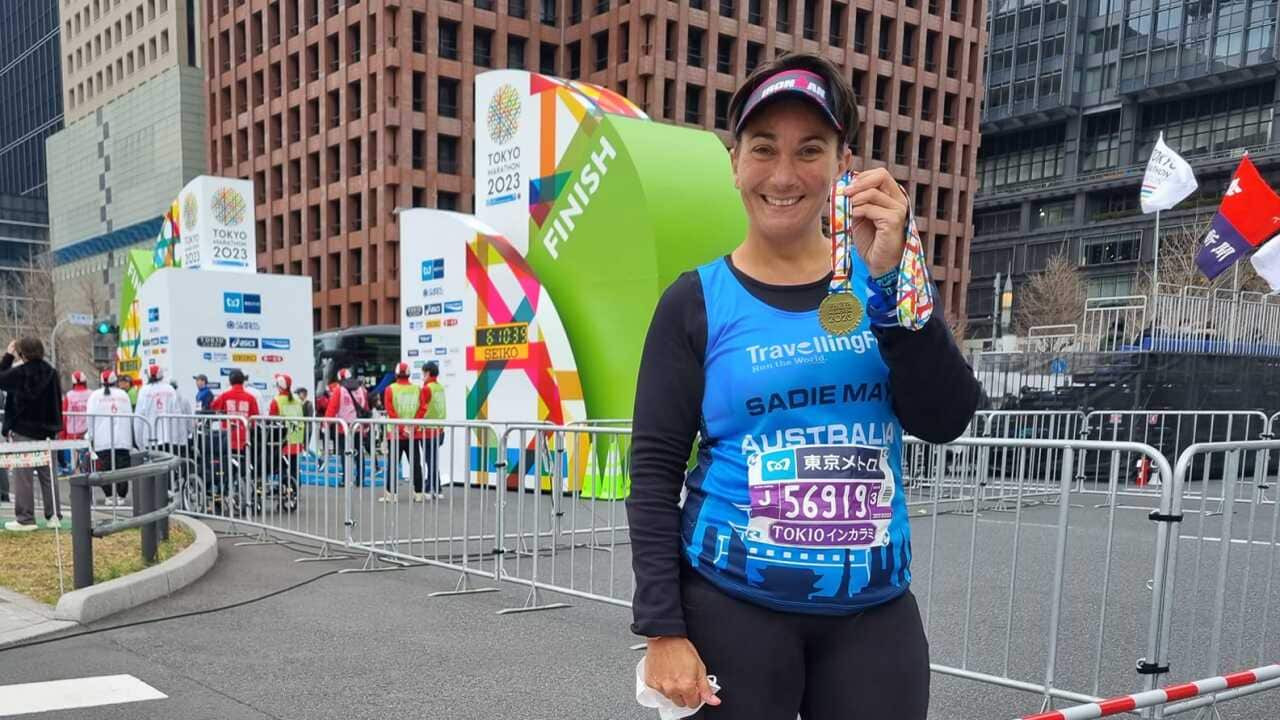 A woman at a race stands holding a medal